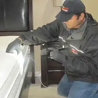 Bed bug inspection technician checking a mattress and bed frame for signs of infestation in Austin, TX