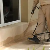 General pest control technician spraying exterior perimeter around a home in Austin, TX