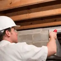 Termite inspection technician checking a basement wall and framing for termite activity in Austin, TX